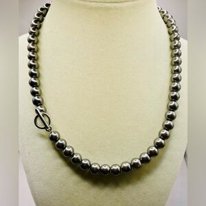 Dark grey faux pearl necklace with a toggle closure. 18 inches. Silver tone.